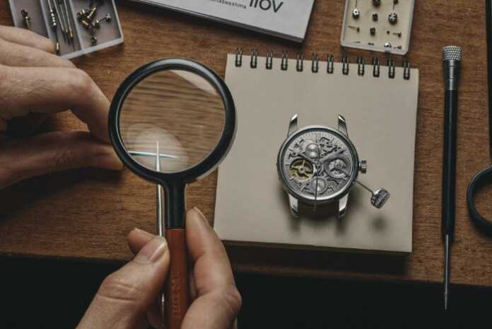 Watch repair profit centre — watchmaker servicing a mechanical movement at the bench