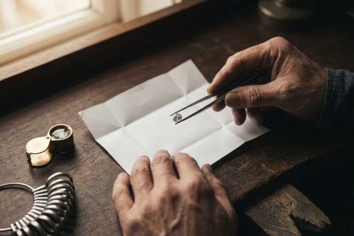 Jeweller holding a loose round brilliant diamond with tweezers, illustrating diamond prices July 2026 for Canadian retailers