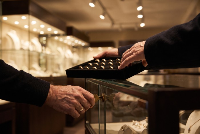 Jeweller locking a display case at closing time to reduce jewellery store robbery losses