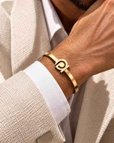 ARAM Jewellery 18K gold monogram cuff worn with a linen jacket